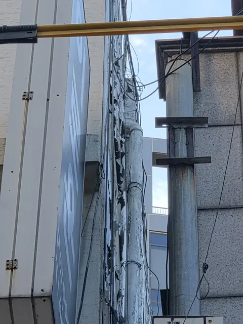 간판 옆 외벽의 도장이 벗겨진 배관 - 시공 전