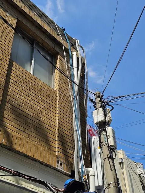 황토색 벽돌 외벽을 따라 올라가는 흰색 배관 - PVC우수관교체 현장