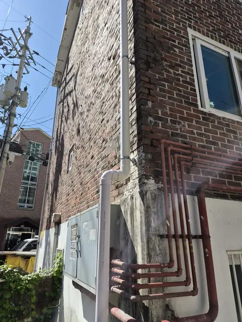 같은 모서리에 흰색 우수관과 고정 클램프가 보이는 모습 - 시공 후